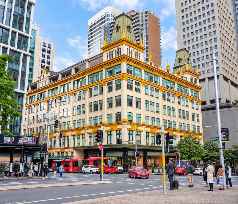 Historic downtown street corner in Sydney with red city buses